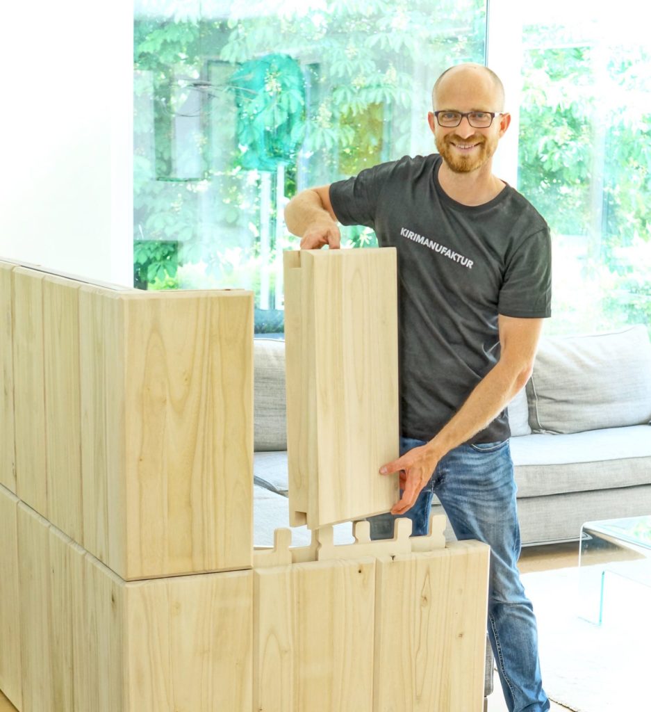 Mann setzt Raumteiler aus Holzmodulen zusammen.